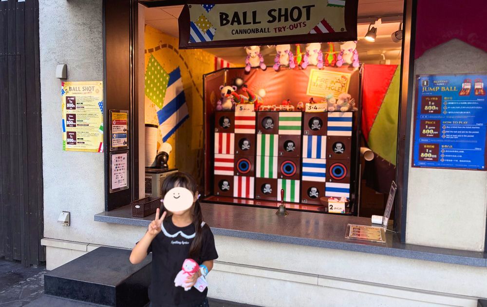 BALL SHOTの前で景品のぬいぐるみを持ってポーズする女の子